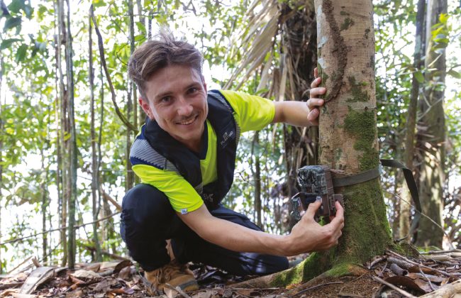 Alexy Tissier installe une caméra de surveillance sur un arbre en forêt guyanaise.