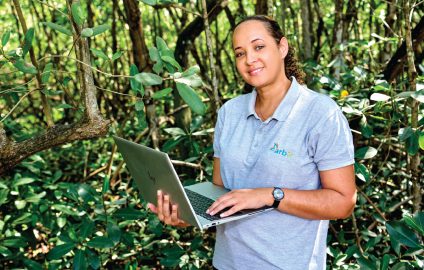 Catherine Hermant dans la mangrove, ordinateur à la main.