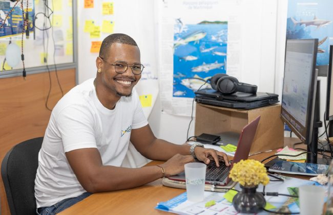 Mathias Diony sourit face à son ordinateur dans les locaux de l’Asso-Mer.