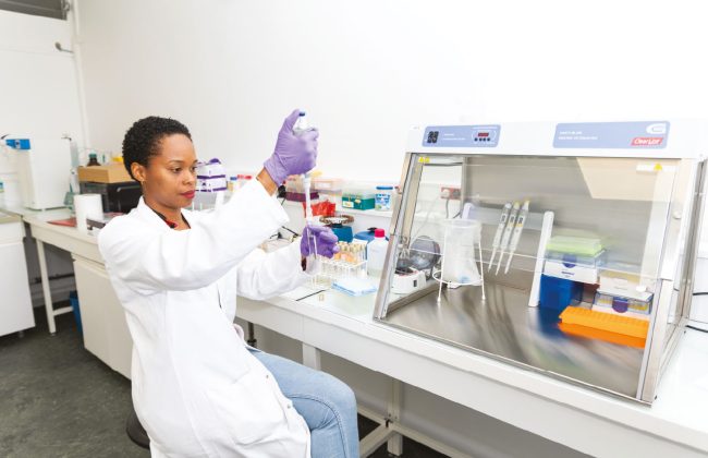 Aurélie Boisnoir en blouse blanche manipulant une pipette dans un laboratoire de microbiologie.