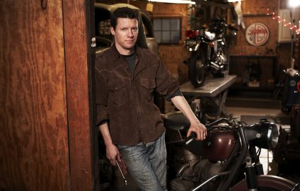 Matthew B. Crawford se tient debout appuyer contre une moto, une clé à molette dans la main