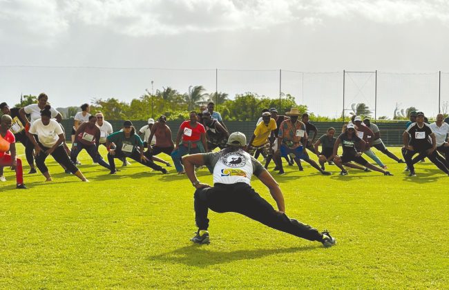 Un animateur sportif sur un stade face à un groupe de personnes qui imitent ses mouvements