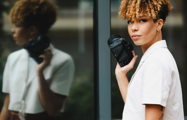 Laetitia Limmois, journaliste, debout face à son reflet devant une vitrine dans les rues de Paris, appareil photo à la main et regard tourné vers la photographe Aubane Nesty