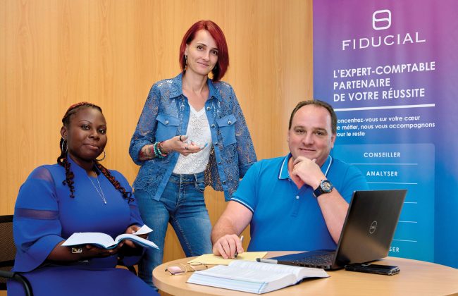 Lindsay Ciette, chef de mission, Alexandra Mauer Godard, directrice d’agence Jarry et Sainte-Rose et Fabien Chagas Dos Santos, directeur de région Antilles Guyane, tous les trois vêtus de bleu autour d'une table à l'agence Fiducial de Sainte-Rose en Guadeloupe